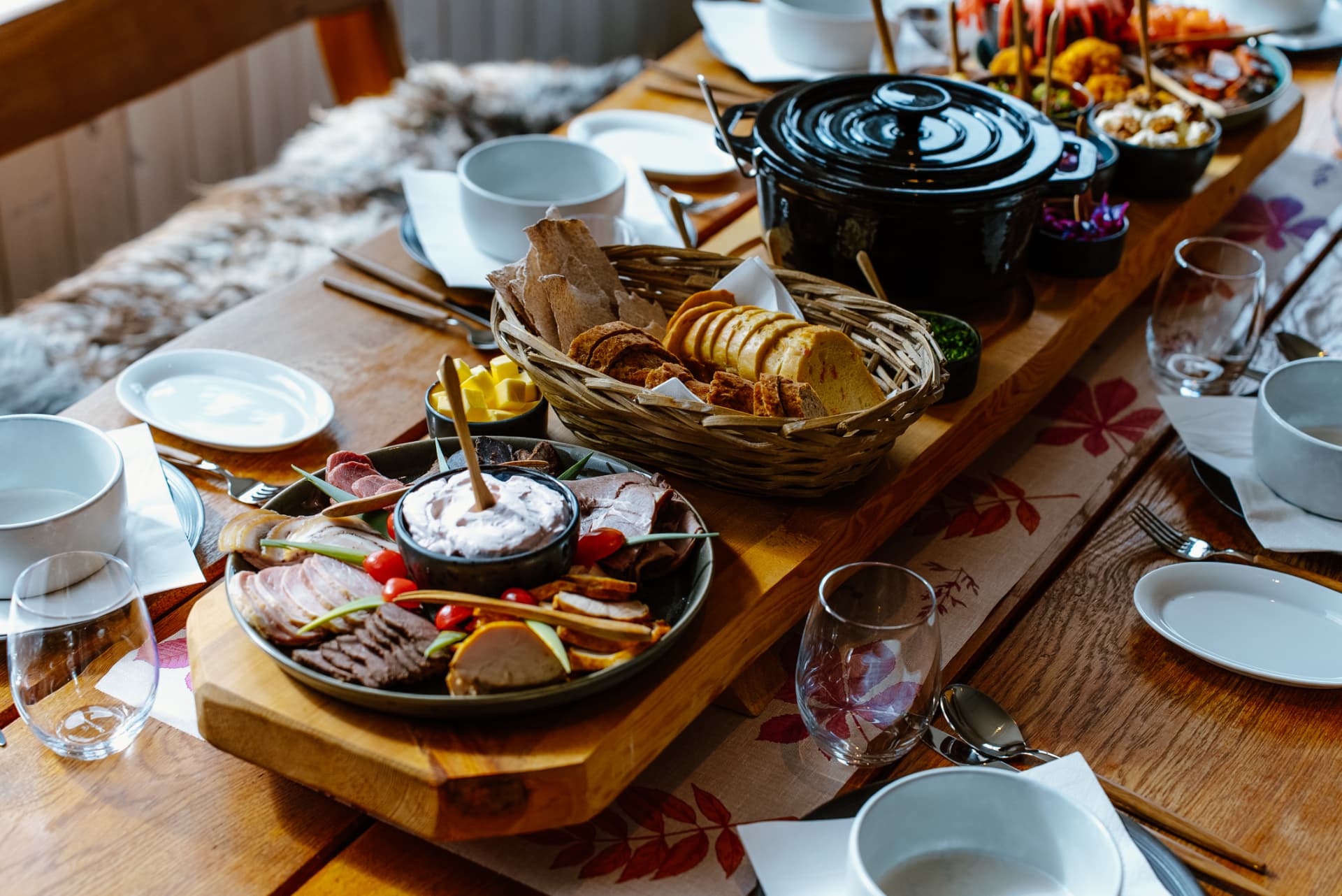 Langbord dekket med fat av lokale råvarer, brødkurv og gryte på Livland Gård